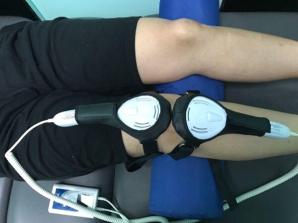 ML830 Smart Laser Console and two Tri-Diode Laser Paddles shown being used on knee of patient for pain relief